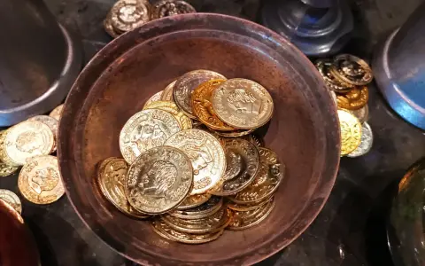 Ein Haufen goldener und silberner Schokoladenmünzen in einer Schale. Sie symbolisieren den Wert und die Bedeutung des 7. Hochzeitstages.