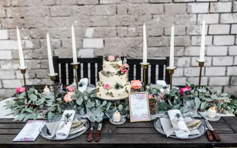 Festlich gedeckter Tisch für eine Hochzeit im Industrial Style mit dreistöckiger Torte, Kerzen und floraler Deko.