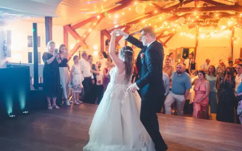 Brautpaar tanzt seinen modernen Hochzeitstanz, umgeben von Gästen und festlicher Beleuchtung.