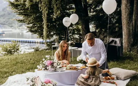 Familie feiert Hochzeit mal anders: Picknick am See mit Ballons und Blumen.