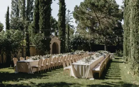 Festlich gedeckte lange Tafel im Garten, umgeben von Zypressen und Bäumen. Perfekt für Hochzeitslocation-Fragen.