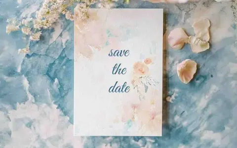Eine Save the Date Karte mit zarten Aquarellblumen auf blauem Marmorgrund.