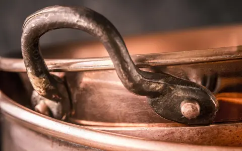Nahaufnahme eines alten Kupferkessels mit Griff. Die Patina erzählt Geschichten, wie die **7 Jahre Ehe Bedeutung** haben, die sich in der Tiefe des Materials widerspiegelt.