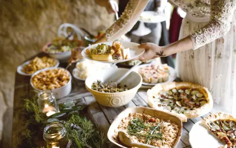 Festliches Buffet mit vielen Köstlichkeiten, perfekt für eine vegane Hochzeit. Teller werden mit leckerem Essen gefüllt.