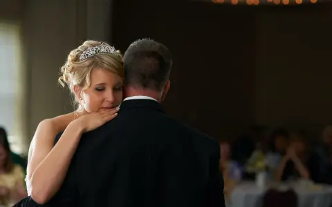 Ein zärtlicher Vater-Tochter-Tanz. Die Braut mit Diadem lehnt sich an ihren Vater, der einen schwarzen Anzug trägt.