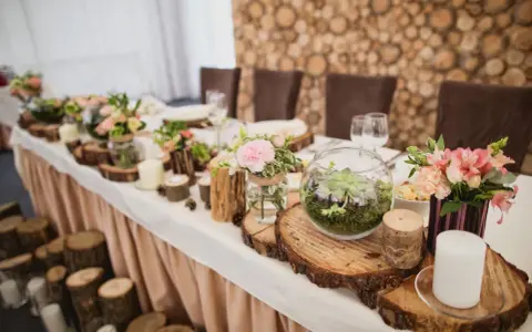 Festlich gedeckter Tisch mit Holzdeko und Blumen. Ein Terrarium und Kerzen unterstreichen die Bedeutung des 5. Hochzeitstags.