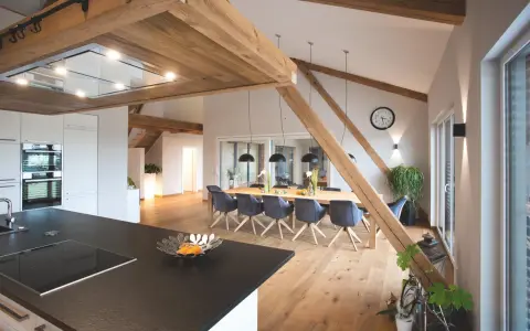 Rustikale Holzbalken und ein langer Esstisch schaffen eine gemütliche Atmosphäre, perfekt für eine Scheune Hochzeit.