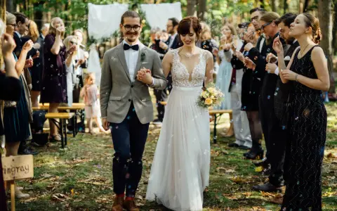 Brautpaar schreitet durch Seifenblasen, Gäste feiern Hochzeit locker.