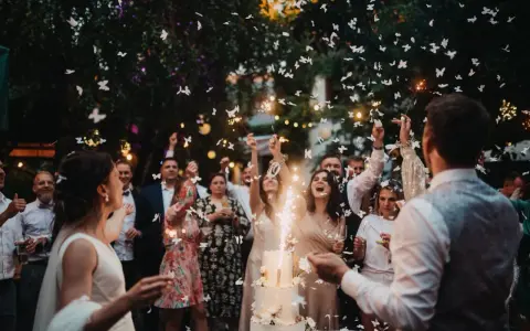 Fröhliche wedding party mit Funken sprühenden Wunderkerzen und flatternden Schmetterlingen aus Papier.
