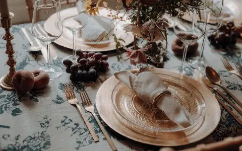 Herbstliche tischdeko hochzeit mit Trauben, Pfirsichen und goldenem Geschirr.