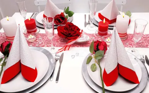 Festlich gedeckter Tisch für eine rot-weiße Hochzeit. Rote Rosen und Kerzen sorgen für romantische Stimmung.