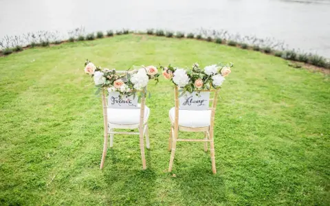 Zwei festlich geschmückte Stühle im Grünen, bereit für eine goldene Hochzeit im kleinen Kreis. "Forever" und "Always" stehen für die Ewigkeit.