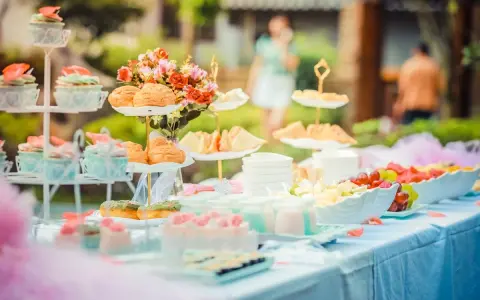 Festlich gedeckte Tafel mit Cupcakes, Gebäck, Obst und Blumen. Perfekte hochzeitsmotto ideen für ein süßes Buffet im Freien.