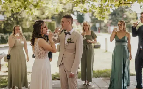Brautpaar und Gäste stoßen beim Sekt­empfang Hochzeit an.