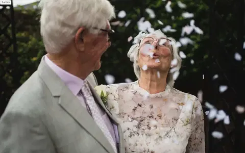 Ein glückliches Paar, meine Eltern, feiern diamantene Hochzeit. Konfetti fliegt durch die Luft, während sie sich anlächeln.