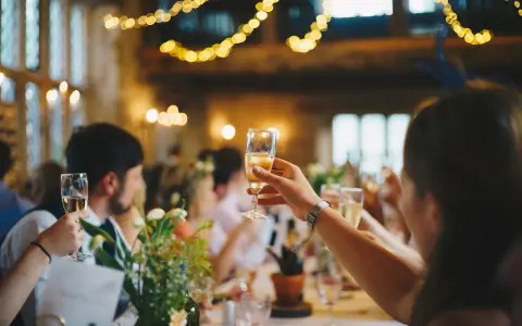 Gäste stoßen mit Sekt an, Lichterketten leuchten. Eine Einladung zur after wedding party.