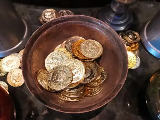 Ein Haufen goldener und silberner Schokoladenmünzen in einer Schale. Sie symbolisieren den Wert und die Bedeutung des 7. Hochzeitstages.