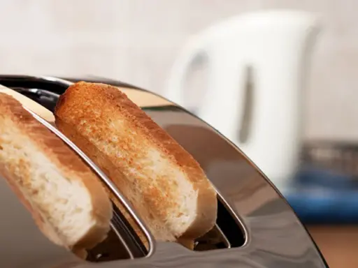 Zwei goldbraune Scheiben Toastbrot ragen aus einem glänzenden Toaster. Ein perfekter Moment, um einen Toast auszusprechen.