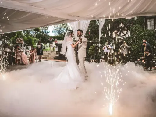 Brautpaar tanzt inmitten von Bodennebel und Funkenregen. Ein romantischer Moment, wie aus umgeschriebene Lieder zur Hochzeit.