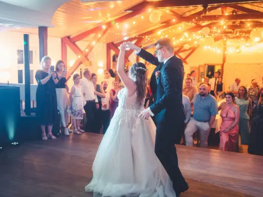 Brautpaar tanzt seinen modernen Hochzeitstanz, umgeben von Gästen und festlicher Beleuchtung.