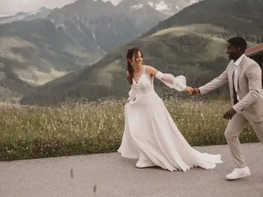 Ein glückliches Brautpaar läuft Hand in Hand vor einer Bergkulisse. Ein wunderschöner Moment für jeden weddingfilm.