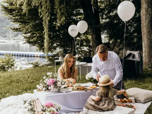 Familie feiert Hochzeit mal anders: Picknick am See mit Ballons und Blumen.