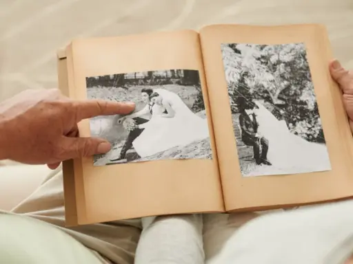 Ein älteres Paar blättert in einem Fotoalbum. Ein Finger zeigt auf ein Hochzeitsfoto. Wie viele Jahre ist die Gnadenhochzeit her?