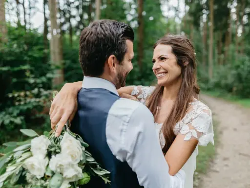 Ein glückliches Brautpaar umarmt sich im Wald. Sie wollten heimlich heiraten und genießen diesen intimen Moment.