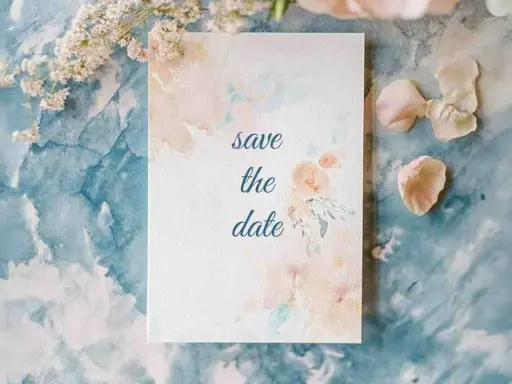 Eine Save the Date Karte mit zarten Aquarellblumen auf blauem Marmorgrund.