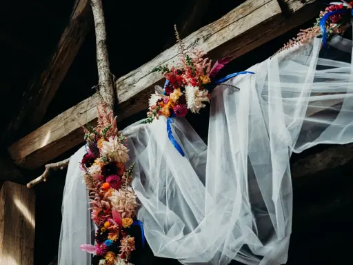Blumenbogen mit Schleier unter Holzbalken, ein romantischer Ort für eine Feier, vielleicht zum 5 Jahre verheiratet Jubiläum.