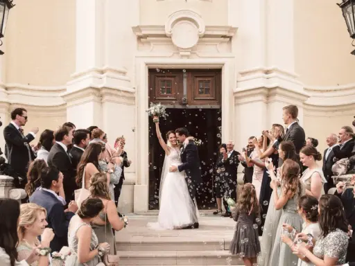 Ein strahlendes Brautpaar verlässt die Kirche, umgeben von Seifenblasen und jubelnden Gästen. Eine klassische Hochzeit voller Freude und Romantik.