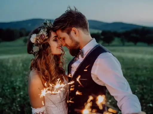 Ein Brautpaar feiert seine elopement hochzeit im Freien bei Einbruch der Dunkelheit mit Wunderkerzen.