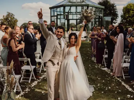 Glückliches Brautpaar feiert den Beginn des Hochzeitsablaufplans. Gäste applaudieren bei der Zeremonie im Freien.