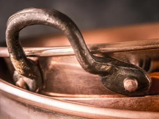 Nahaufnahme eines alten Kupferkessels mit Griff. Die Patina erzählt Geschichten, wie die **7 Jahre Ehe Bedeutung** haben, die sich in der Tiefe des Materials widerspiegelt.