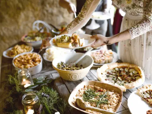 Festliches Buffet mit vielen Köstlichkeiten, perfekt für eine vegane Hochzeit. Teller werden mit leckerem Essen gefüllt.