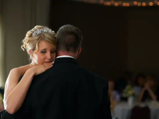 Ein zärtlicher Vater-Tochter-Tanz. Die Braut mit Diadem lehnt sich an ihren Vater, der einen schwarzen Anzug trägt.