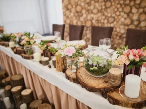 Festlich gedeckter Tisch mit Holzdeko und Blumen. Ein Terrarium und Kerzen unterstreichen die Bedeutung des 5. Hochzeitstags.