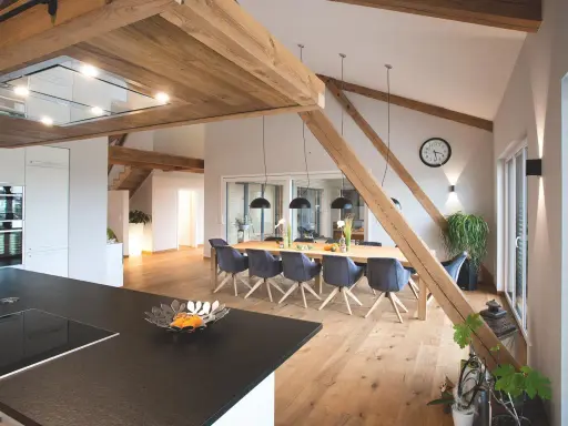 Rustikale Holzbalken und ein langer Esstisch schaffen eine gemütliche Atmosphäre, perfekt für eine Scheune Hochzeit.