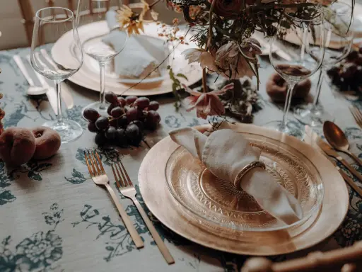 Herbstliche tischdeko hochzeit mit Trauben, Pfirsichen und goldenem Geschirr.