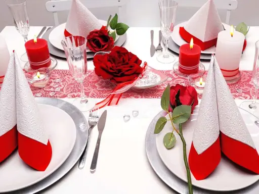 Festlich gedeckter Tisch für eine rot-weiße Hochzeit. Rote Rosen und Kerzen sorgen für romantische Stimmung.