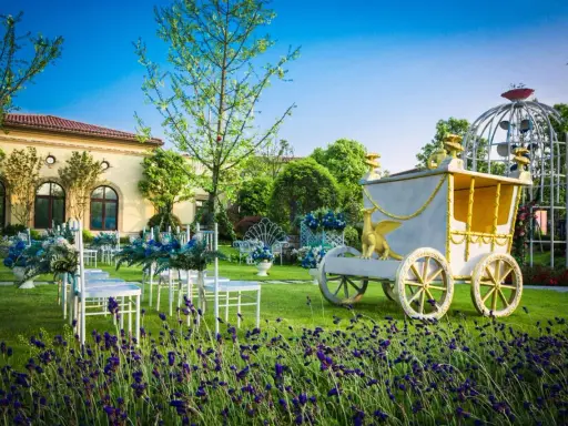 Märchenhafte Kutsche und Sitzreihen im Garten deuten auf eine unkonventionelle Hochzeit hin.