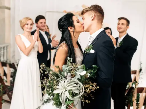 Brautpaar küsst sich, Gäste applaudieren. Der Beginn der standesamtlichen hochzeit ablauf ist ein emotionaler Moment.