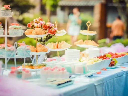 Festlich gedeckte Tafel mit Cupcakes, Gebäck, Obst und Blumen. Perfekte hochzeitsmotto ideen für ein süßes Buffet im Freien.