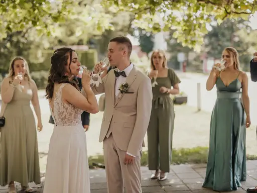 Brautpaar und Gäste stoßen beim Sekt­empfang Hochzeit an.