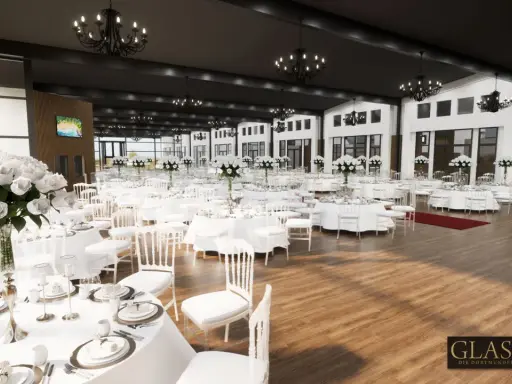Elegante Glashaus Hochzeitslocation mit vielen weiß gedeckten Tischen, weißen Stühlen und üppigen Blumenarrangements.