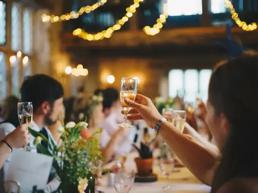 Gäste stoßen mit Sekt an, Lichterketten leuchten. Eine Einladung zur after wedding party.