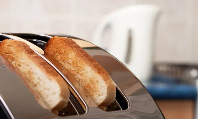 Zwei goldbraune Scheiben Toastbrot ragen aus einem glänzenden Toaster. Ein perfekter Moment, um einen Toast auszusprechen.