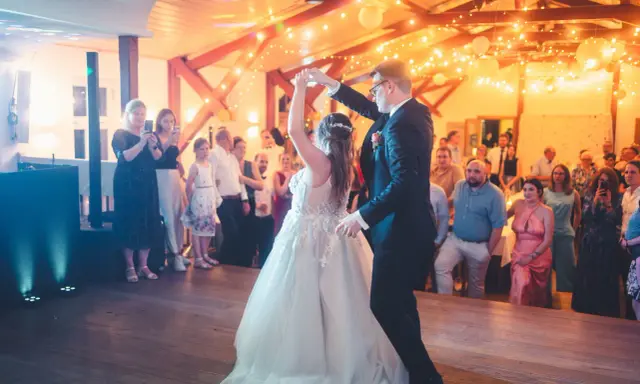 Brautpaar tanzt seinen modernen Hochzeitstanz, umgeben von Gästen und festlicher Beleuchtung.