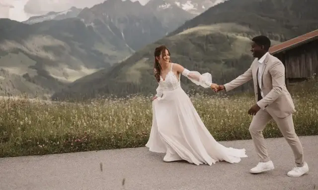 Ein glückliches Brautpaar läuft Hand in Hand vor einer Bergkulisse. Ein wunderschöner Moment für jeden weddingfilm.