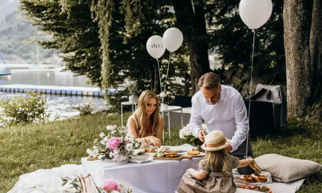 Familie feiert Hochzeit mal anders: Picknick am See mit Ballons und Blumen.